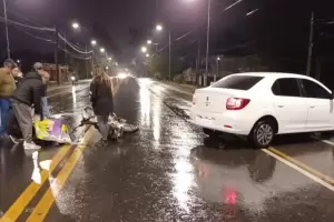 Un automvil colision con un motociclista y esperan a la ambulancia bajo la lluvia