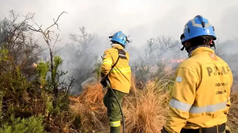 Personas parte de un grupo de bomberos y vecinos autogestionados combaten un incendio forestal este lunes, en Intiyaco en las cercanas de Villa Berna