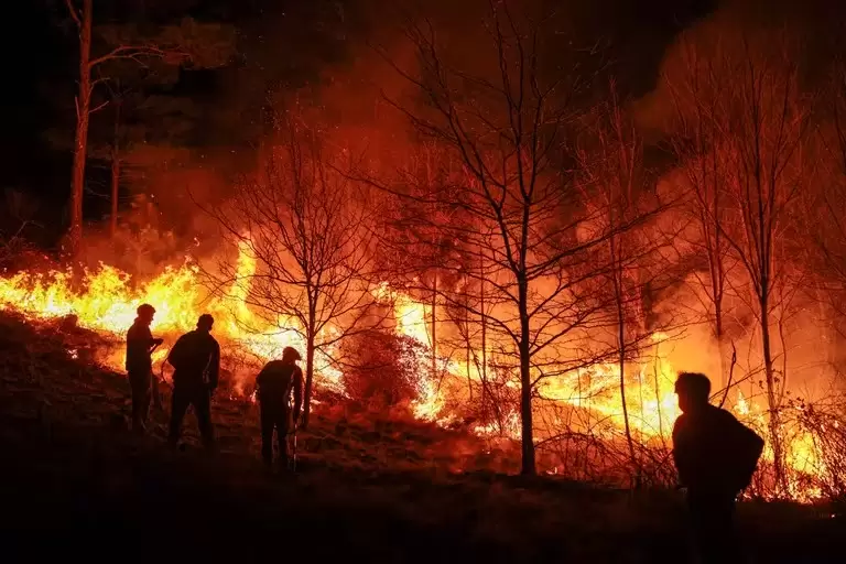 Personas parte de un grupo de bomberos y vecinos autogestionados combaten un incendio forestal este lunes, en Intiyaco en las cercanas de Villa Berna